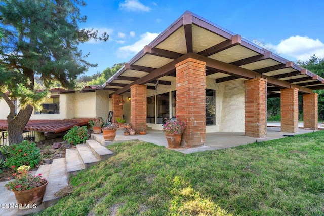 rear view of house with a lawn and a patio