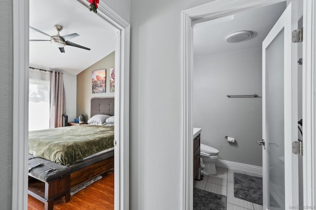 bedroom with ceiling fan, ensuite bathroom, and vaulted ceiling