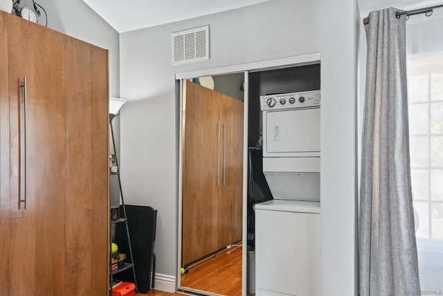 laundry area with stacked washer and dryer and light hardwood / wood-style flooring