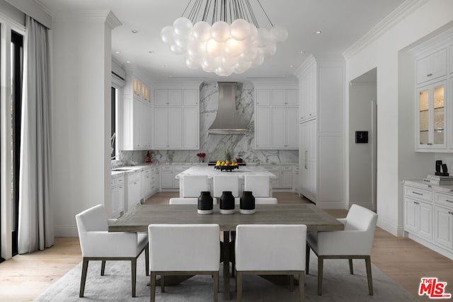 dining room featuring light hardwood / wood-style floors, ornamental molding, and an inviting chandelier