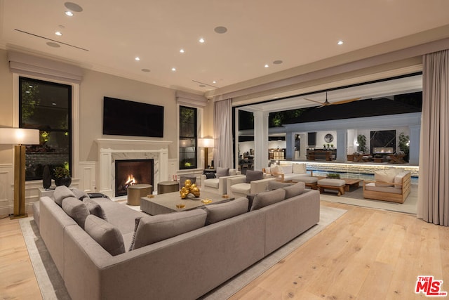 living room with ceiling fan, a high end fireplace, and light hardwood / wood-style floors