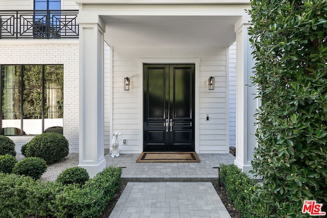 entrance to property with covered porch and a balcony