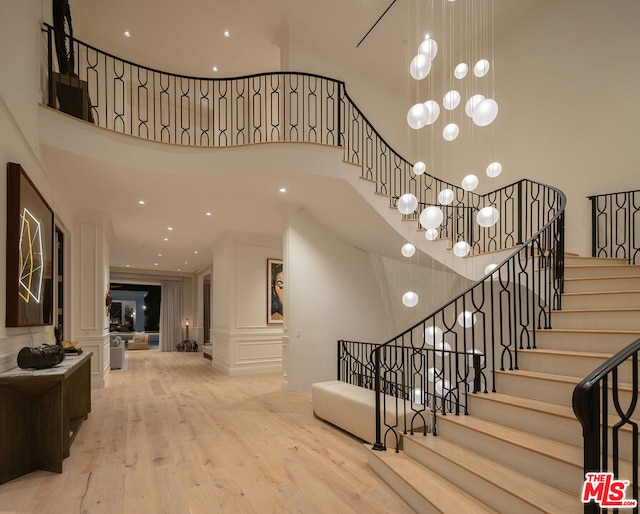 stairs featuring an inviting chandelier, ornate columns, a towering ceiling, and hardwood / wood-style floors