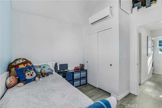 bedroom featuring an AC wall unit, a closet, and light wood-type flooring