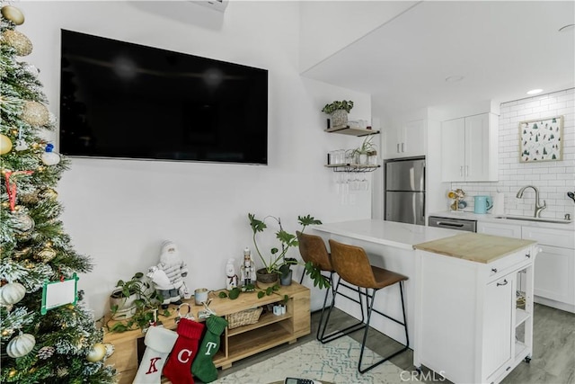 kitchen featuring stainless steel appliances, backsplash, a kitchen breakfast bar, white cabinets, and sink