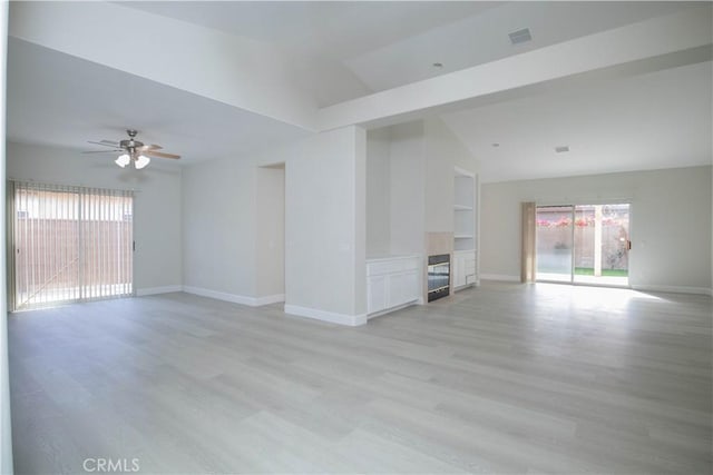 unfurnished living room with ceiling fan, a wealth of natural light, lofted ceiling, and light hardwood / wood-style floors