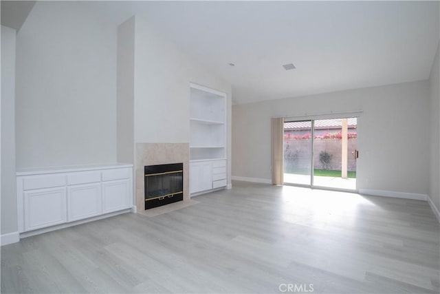 unfurnished living room featuring light hardwood / wood-style flooring, built in features, and a fireplace