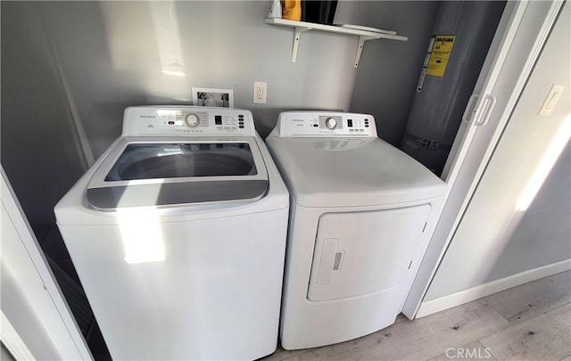 laundry room featuring gas water heater, washing machine and dryer, and light wood-type flooring