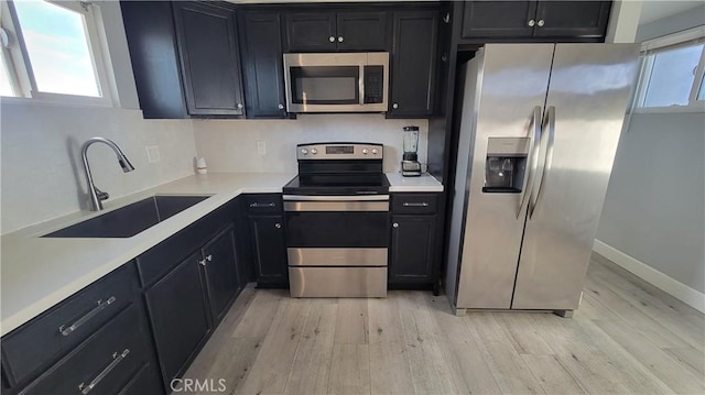 kitchen with sink, stainless steel appliances, and light hardwood / wood-style flooring