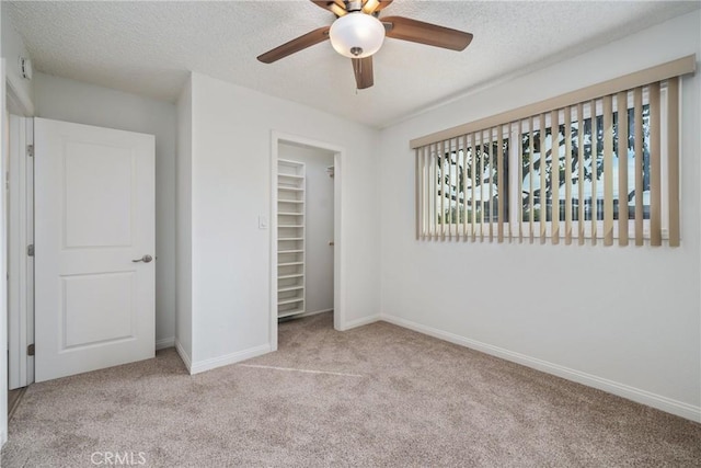 unfurnished bedroom with light carpet, ceiling fan, a closet, and a textured ceiling