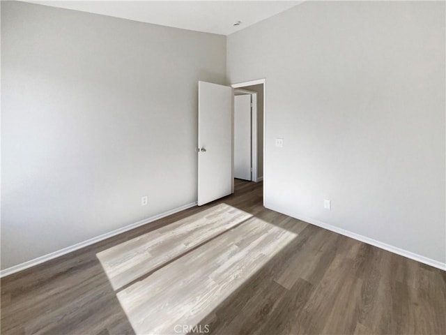 empty room featuring lofted ceiling and dark hardwood / wood-style floors