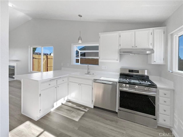 kitchen with stainless steel appliances, decorative light fixtures, kitchen peninsula, and white cabinets