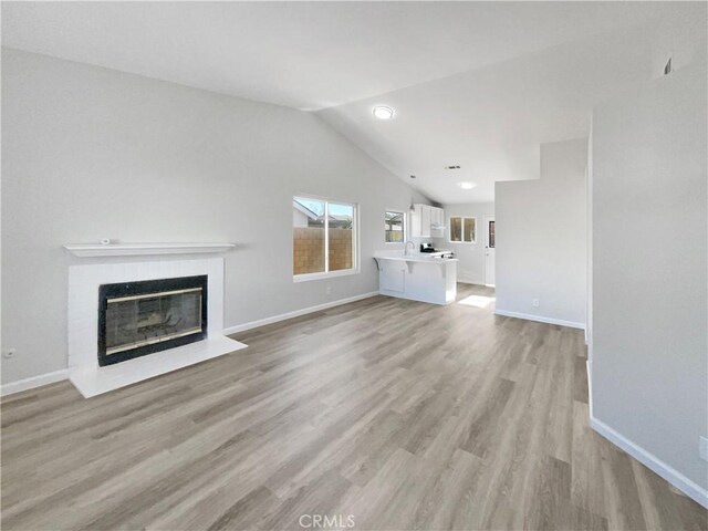 unfurnished living room with light wood-type flooring and vaulted ceiling