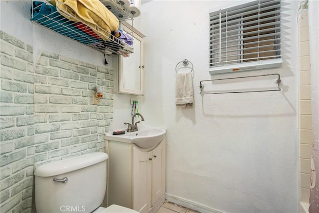 bathroom with brick wall, toilet, vanity, and a shower with curtain