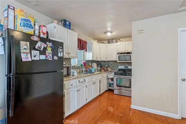 kitchen with black appliances, white cabinetry, tasteful backsplash, sink, and light stone counters