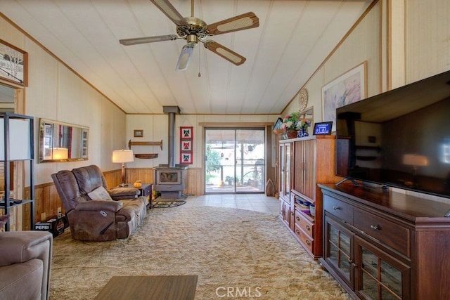 living room featuring a wood stove, ceiling fan, light colored carpet, and wood walls