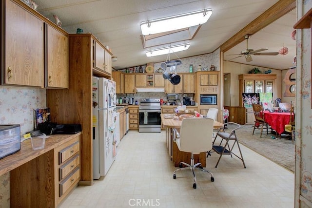 kitchen featuring ceiling fan, appliances with stainless steel finishes, and vaulted ceiling with beams