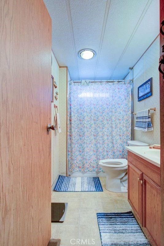 bathroom featuring a textured ceiling, toilet, vanity, and a shower with shower curtain