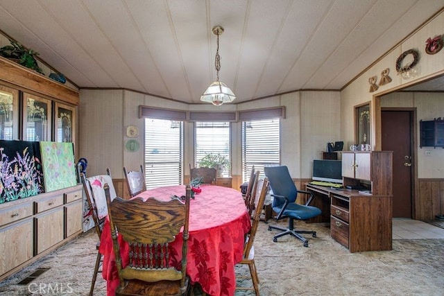 dining room with wood walls, light colored carpet, and lofted ceiling