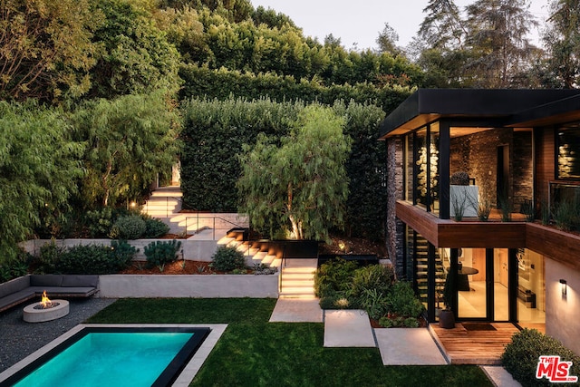 view of swimming pool with an outdoor fire pit and a yard