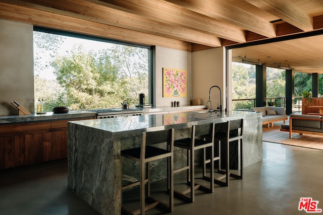 bar with beam ceiling, dark stone counters, and sink