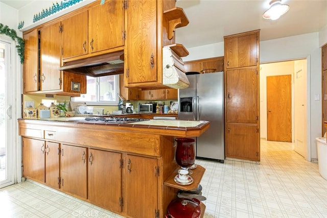 kitchen featuring kitchen peninsula, stainless steel appliances, and tile countertops