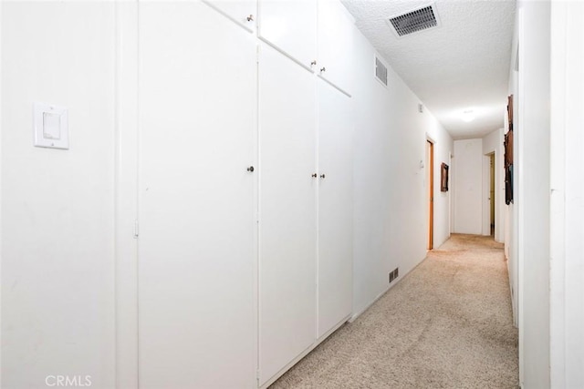 hall featuring light colored carpet and a textured ceiling