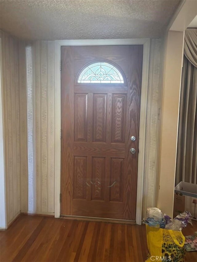 entrance foyer with a textured ceiling, wood walls, and wood-type flooring