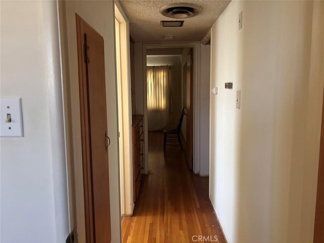 corridor featuring hardwood / wood-style flooring and a textured ceiling