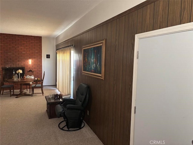 living area featuring light carpet, a brick fireplace, and wood walls