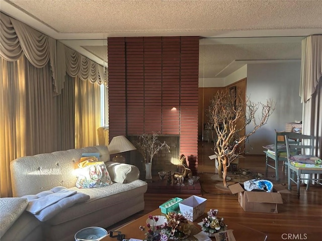 living room with a brick fireplace, a textured ceiling, and hardwood / wood-style flooring