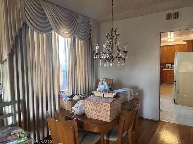 dining area featuring a textured ceiling, dark hardwood / wood-style floors, and a notable chandelier