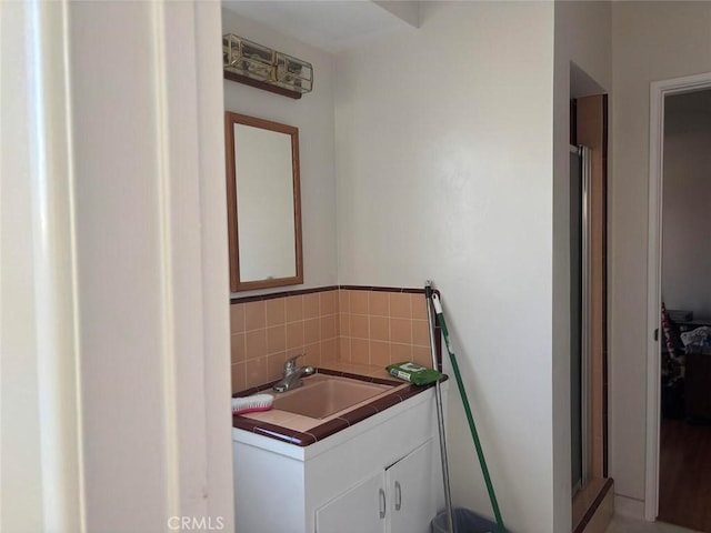 bathroom featuring a shower with shower door, tasteful backsplash, and vanity