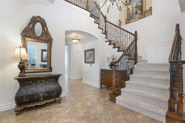 tiled foyer with a towering ceiling and a chandelier