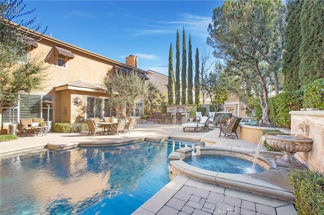 view of swimming pool featuring a patio, pool water feature, and an in ground hot tub