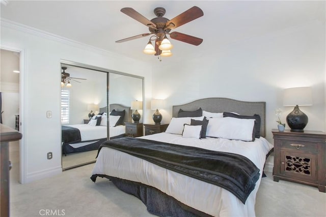 bedroom featuring light carpet, crown molding, a closet, and ceiling fan