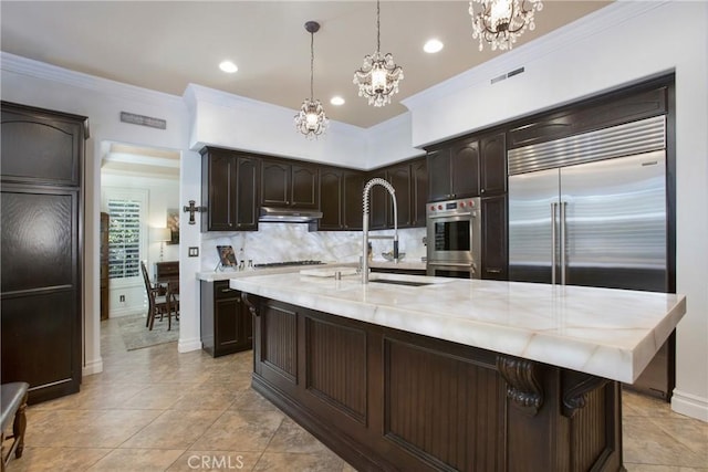 kitchen with appliances with stainless steel finishes, decorative light fixtures, sink, backsplash, and dark brown cabinets