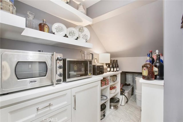 kitchen with white cabinetry and vaulted ceiling