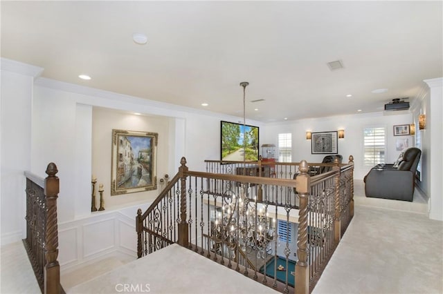 hallway featuring crown molding, an inviting chandelier, and carpet