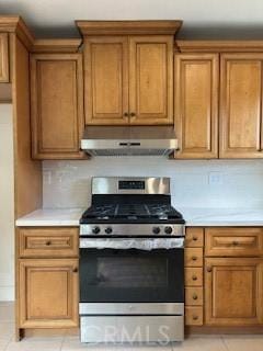 kitchen featuring decorative backsplash, stainless steel range with gas stovetop, and light tile patterned flooring