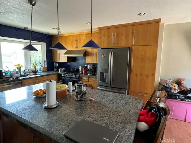 kitchen with appliances with stainless steel finishes, wood-type flooring, sink, backsplash, and hanging light fixtures