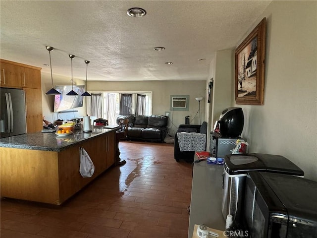 kitchen with decorative light fixtures, dark wood-type flooring, stainless steel fridge, and a textured ceiling