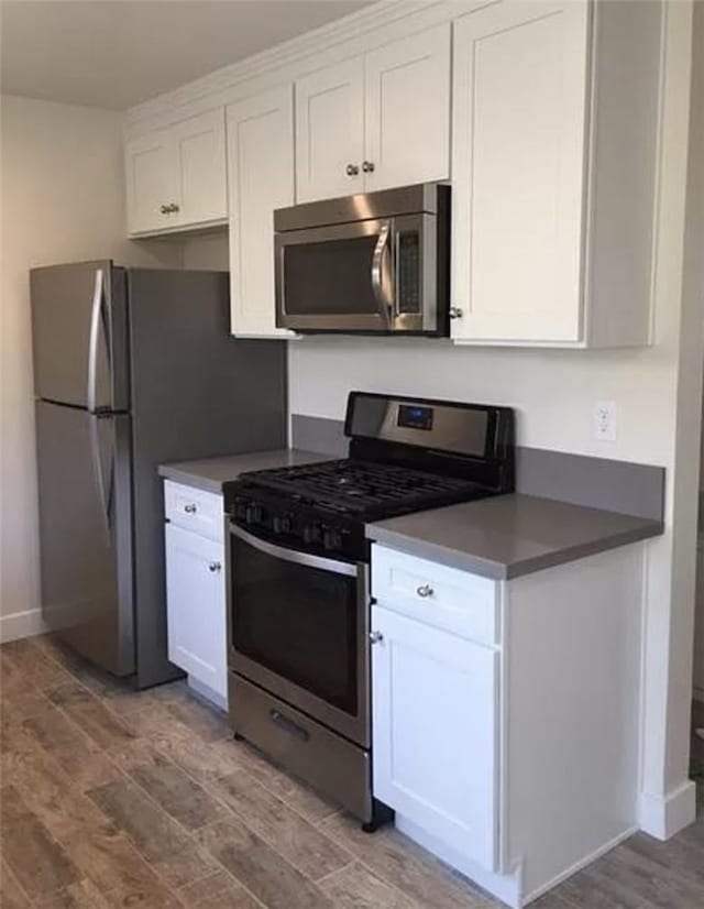 kitchen with light wood-type flooring, appliances with stainless steel finishes, and white cabinetry