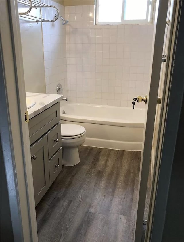 full bathroom featuring hardwood / wood-style floors, toilet, vanity, and tiled shower / bath combo