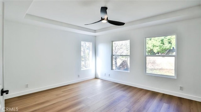 unfurnished room with a raised ceiling, ceiling fan, and hardwood / wood-style floors