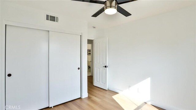 unfurnished bedroom featuring ceiling fan, a closet, and light hardwood / wood-style flooring