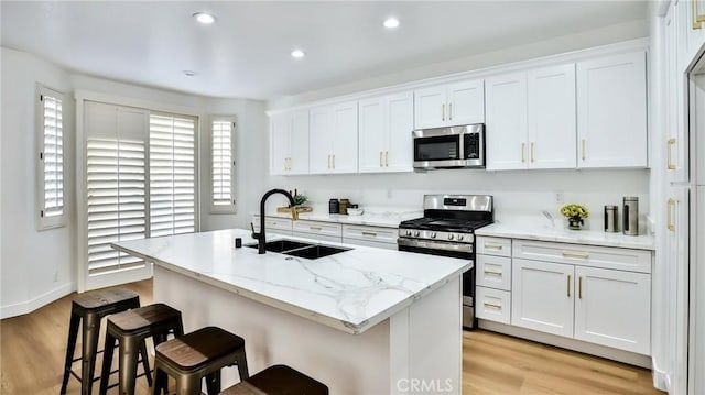 kitchen featuring sink, white cabinets, a center island with sink, and stainless steel appliances