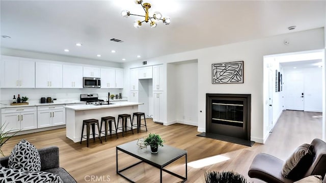 living room featuring an inviting chandelier, light hardwood / wood-style floors, and sink