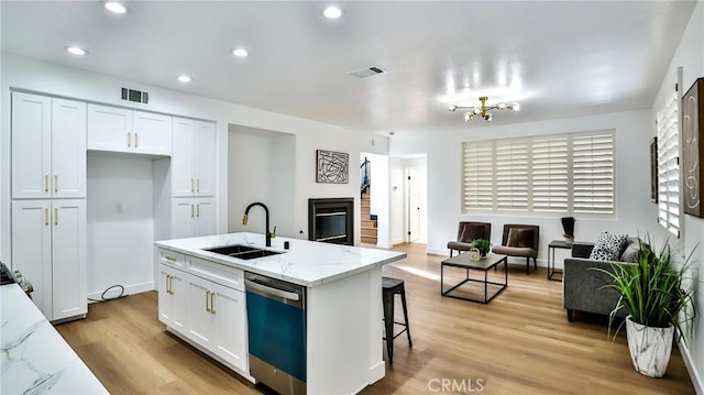 kitchen with light stone counters, sink, white cabinetry, and stainless steel dishwasher