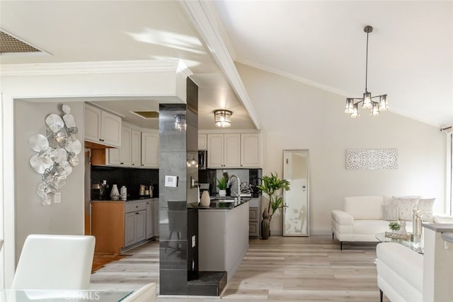 kitchen with decorative light fixtures, backsplash, light wood-type flooring, and ornamental molding